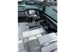 Cockpit of a white speedboat showing a black steering wheel, navigation screen, throttle controls, and white cushioned seats.