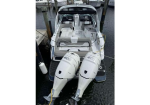 White motorboat docked at a marina with twin outboard engines at the stern.