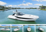 White luxury motor yacht anchored in a calm turquoise canal with palm-lined houses in the background.
