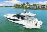 White luxury motor yacht anchored on turquoise water near a palm‑lined residential shoreline]**