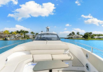 White luxury motorboat on turquoise canal with palm-lined shore and blue sky.