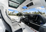 Luxurious boat cockpit with white captain seats and a modern black dashboard overlooking sunny waterfront.