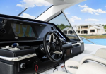 Helm of a modern luxury speedboat with a steering wheel and navigation display, near a shoreline house in the background.