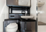 Small modern bathroom with a white toilet on the left, a white vessel sink on a black counter, and metallic storage cabinets above; compact and minimalistic setup.