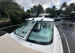 White motor yacht docked along a canal with palm trees and houses in the background.