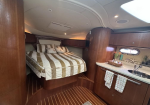 Luxurious yacht cabin with a centered bed, striped quilt, and matching pillows against wood-paneled walls