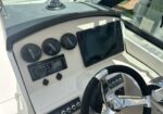 Boat helm with Garmin GPS/chartplotter, Fusion stereo, three black gauge caps labeled Garmin, compass on dash, and a chrome steering wheel on the right.