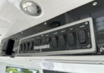 Close-up of a silver-framed boat switch panel labeled Everglades with rocker switches for Flood Fwd, Flood Aft, Aux, and Awning