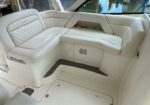 White leather boat lounge with a U-shaped seat, diamond-stitched backrest, and built-in storage pocket under the windowed side panel.