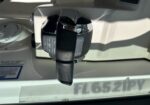 Close-up of an aircraft throttle lever with a glossy chrome knob and surrounding control panel in a light-colored cockpit interior.
