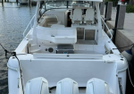 White motor yacht docked at a marina with three large outboard engines at the stern and Garmin radar equipment on top.