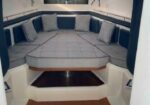 U-shaped grey sofa with blue cushions around a raised deck in a boat cabin.