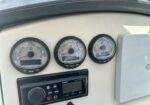 Boat dashboard with three round gauges (RPM, speed, and additional readout) on a beige panel, with a Fusion stereo unit beneath.