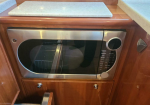 Built-in stainless steel microwave in a wooden cabinet with a glass door and right-side control panel.