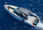 Speedboat speeding across deep blue ocean with two people on board and wake trailing behind.