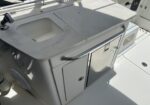 Outdoor boat galley counter with built-in sink, faucet, and white storage cabinets on a sunlit deck