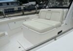White cushioned rear cockpit seating on a luxury boat at a marina, with a small backrest and chrome railings nearby