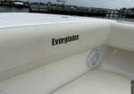 White boat seating area with the Everglades logo and a built-in round speaker, with a marina in the background.