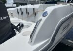 White Boston Whaler boat cockpit with chrome grab rails, rope lines, and an outboard Mercury engine cover in view.