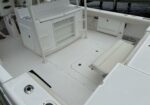 White boat cockpit with built-in storage, seating, and a clean deck near a docked boat area.