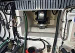 Boat bilge pump installation in a marine engine compartment, with a central black motor and metal flange surrounded by hoses and wiring