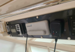 Garmin marine electronics mounted on a textured panel: a GPS/chartplotter unit and a handheld radio with cords attached.