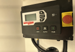 Industrial control panel with LCD screen, directional buttons, Enter, and Run/Auto/Off switches; red emergency stop on yellow housing to the right.