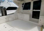 White yacht deck interior with built-in cabinets and storage, a foldable ladder mounted on the wall, and a view of another boat through a windowed area