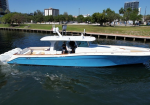 White and blue luxury motorboat cruising in a canal with urban shoreline and trees in the background