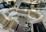 Wraparound boat seating with beige patterned cushions around a white table, at the cockpit of a motorboat.