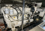 Diesel generator engine in a machine room, showing fuel filters, hoses, and wiring.