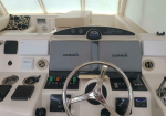 Boat helm with two Garmin display screens, a chrome steering wheel, and navigation controls on a white yacht console
