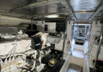 Boat engine room with a large white diesel engine, wiring, and a control panel in the cramped machinery space of a yacht.