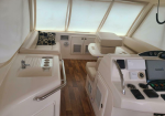 White luxury boat cabin with helm station on the right and a padded captain’s seat; built-in electronics including a Garmin display visible at the console.