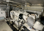Large diesel generator in a confined mechanical room with white engine, hoses, and wiring visible.
