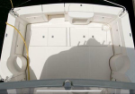 Top-down view of a white boat cockpit with built-in storage compartments and seating along the sides, a yellow rope curving along the left edge.
