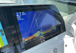 Boat cockpit command screen showing depth 27.0 ft and sonar graph beside water, Garmin display on a boat console