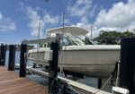 White motorboat on a boat lift at a wooden dock by calm water under a blue sky with clouds edge. (informative)