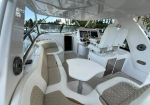 Luxurious white yacht cockpit with beige cushioned seating around a white table and a captain's chair at the helm.