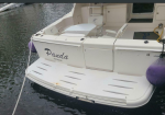 White motorboat named Panda with Montego Bay text, docked in calm water; purple fenders hung along the stern and a rear swim platform visible.