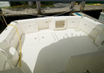 Open stern cockpit of a white boat with built-in storage lockers and hatch covers, mooring lines tied to a dock in the background.