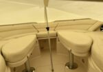 Cream-colored boat cockpit seating with cushioned benches and a central pole under a canopy. Aft sunshade enclosure creates a cozy lounge area.