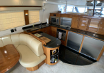 Luxurious yacht galley with wood cabinets, stainless steel appliances, and a curved black granite countertop.