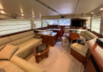 Interior of a luxury yacht cabin: cream leather seating, wood-paneled walls, and a glossy table in a sunlit salon.