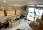 Cozy yacht salon with a beige leather sofa, nautical blue pillows, and a sliding glass door to the deck.