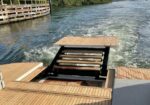 Teak boat deck with a fold-down swim platform lowering into the water.