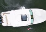 Top-down view of a white yacht on dark water with four blue outboard engines at the stern and an American flag at the rear.