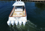 Aerial view of a white luxury motorboat named 'Mary Daniela' with wooden trim and multiple outboard engines at the stern on blue water.