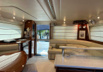 Luxurious yacht interior with cream leather sofa, wooden cabinets, and a speckled countertop island.