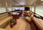 Luxurious yacht salon with cream leather seating, wood cabinetry, and a glass-topped coffee table.